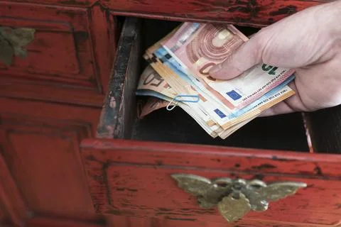 Hand taking stack of paper money from drawer of antique cabinet 스톡 사진