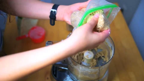 Hand taking suet peanut butter coconut oil wheat flour mixture of food processor Stock Footage 145564656