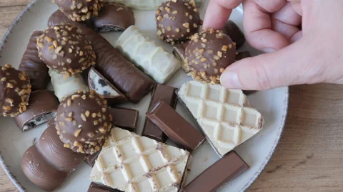Hand is taking sweets from a plate. Chocolates and wafers Stock Footage 342501186