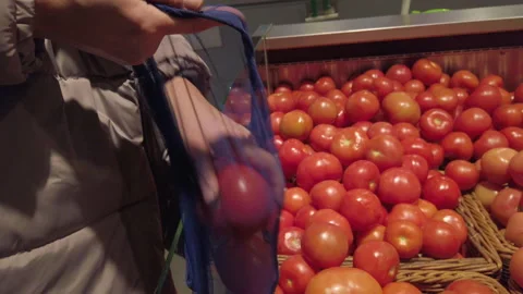 Hand taking tomatoes from shelf with tomatoes at food store, putting in eco bag Видео 144126737