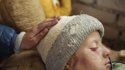 Hand Taps Bruised Boy Head with Tender Care in Cold Shelter Video stock 327020211