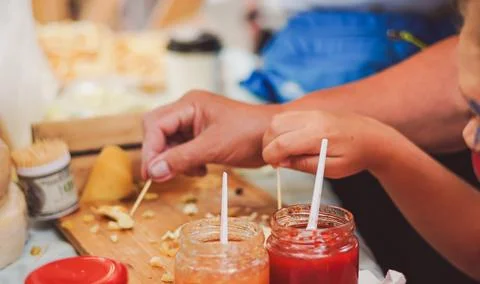Hand tasting string cheese near sauce jars at a food market stall. Stock Photos