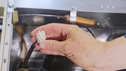 Hand of a technician connects electrical wires inside a refrigerator Stock Footage 336480254