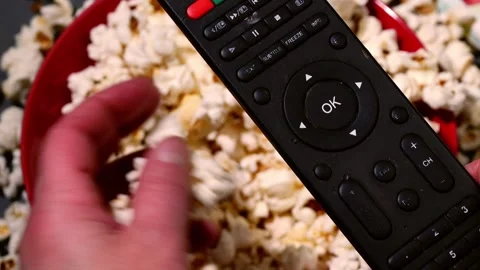 Hand with television remote with popcorn background Stock Footage 250022383