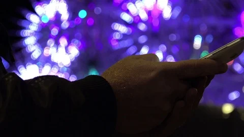 Hand texting messages with a smartphone in front a Christmas tree in the night Stock-Footage 71412138