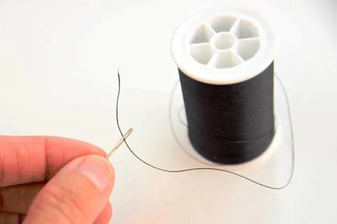 Hand threading a needle with black thread Stock Photos