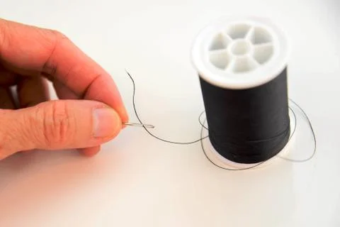 Hand threading a needle with black thread Stock Photos