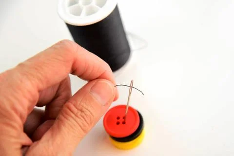 Hand threading a needle with black thread Stock Photos