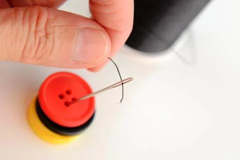 Hand threading a needle with black thread Stock Photos