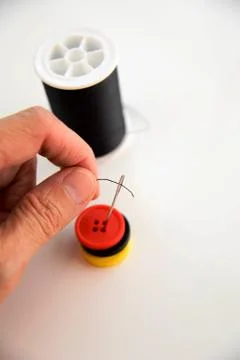 Hand threading a needle with black thread Stock Photos