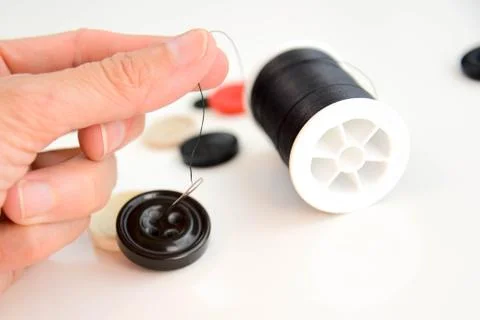 Hand threading a needle with black thread Stock Photos