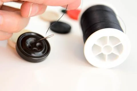 Hand threading a needle with black thread Stock Photos