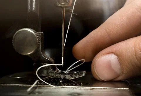 A hand threads a needle in an old retro sewing machine. Tools for the work Stock Photos