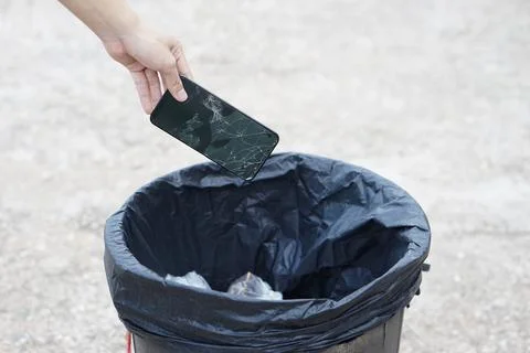 Hand throw broken smartphone into the bin Stock Photos