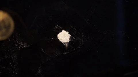 A hand is throwing a bitcoin coin on a pile of cocaine Stock Footage 100332120