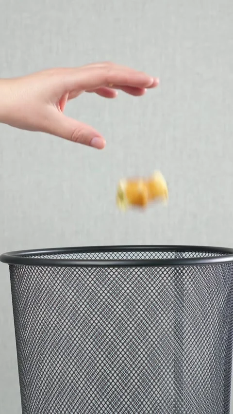 Hand throwing burning paper into a black metal mesh trash can, representing the Stock Footage 342906589