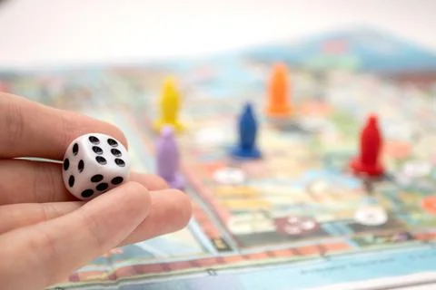 Hand throwing the dice on the board game playing field Stock Photos