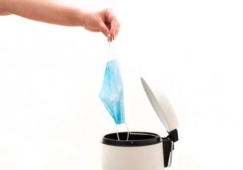 Hand throwing face mask to trash during coronavirus Stock Photos
