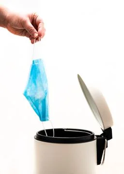 Hand throwing face mask to trash during coronavirus lockdown Stock Photos