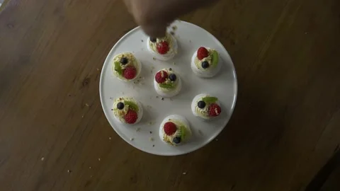 Hand throwing nuts on pavlova cake Vidéo 164917157
