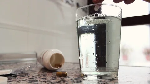 Hand throwing a tablet in glass with water and stir Stock Footage 71363024