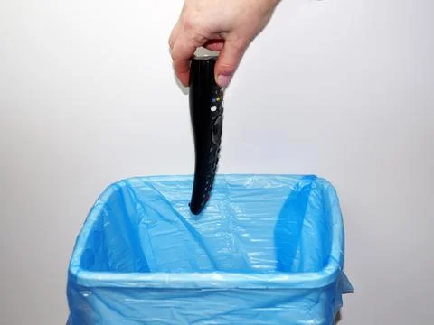 Hand throwing tv remote into trash can Stock Photos
