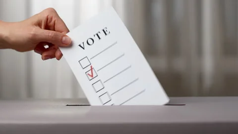 A hand throws a ballot into a box on Election Day. Voting concept. Stock Footage 254012501