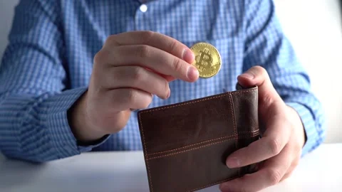 Hand Throws Bitcoin into Wallet. Background Man in Blue Shirt at Home or Office Stock Footage 167213280