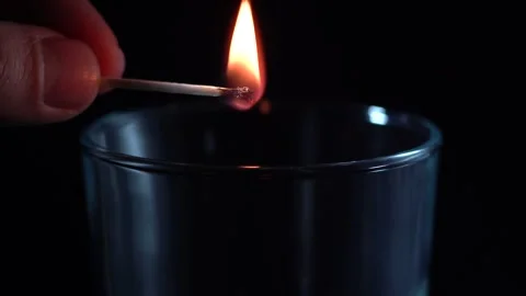 Hand throws a burning match into a glass cup Stock Footage 272174009