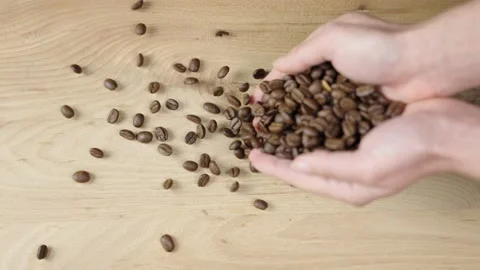 Hand throws coffee beans on a wooden surface Vídeos de archivo 150863301