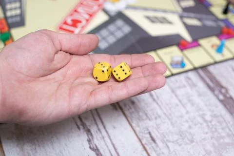 Hand throws dice on the background of colorful blurred fantasy Board games,.. Stock Photos
