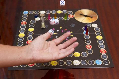 Hand throws the dice on the background of colorful blurred fantasy Board game Stock Photos