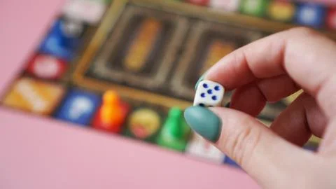 Hand throws the dice on the background of colorful blurred Board games Stock Photos