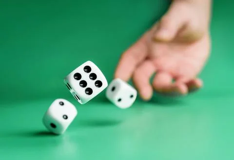 Hand throws dice on a green background with selective focus. Stock Photos