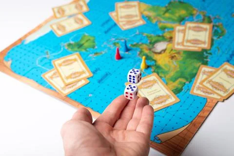 Hand throws dice with numbers on the board game field Stock Photos