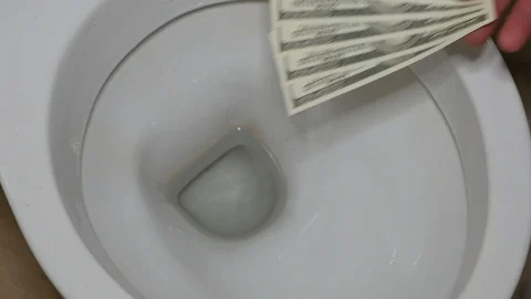Hand throws dollars into the toilet (waste of money) Stock Footage