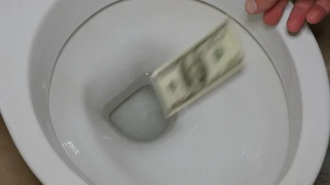 Hand throws dollars into the toilet (waste of money) Stock Footage