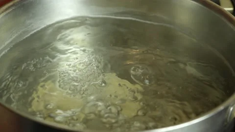 The hand throws the dumplings one by one into the boiling water in the pan Stock Footage 231332244