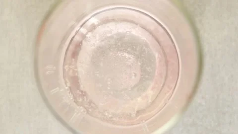 Hand throws effervescent vitamin C tablet into a glass of water, top view Vidéo 234459608
