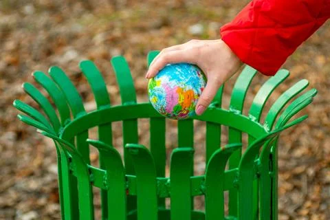 Hand throws a globe into trash can. Hand putting Earth globe in trash bin. Th Stock Photos