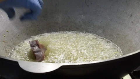 Hand throws meat into a cauldron of boiling oil. Cooking pilaf Stockbeeldmateriaal 114494506