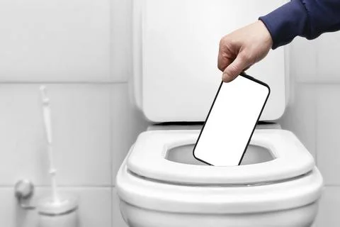 The hand throws the phone with an empty white screen into the toilet or trash Stock Photos