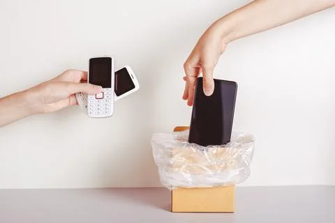 The hand throws the smartphone into the trash and the second hand holds pus.. Stock Photos