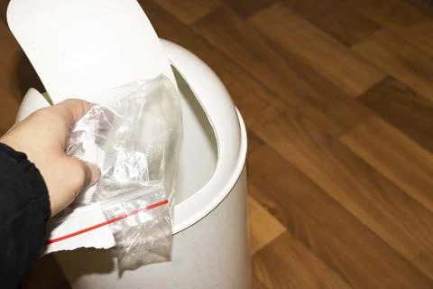 Hand throws trash into trash can on wooden background Stock Photos