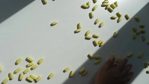 Hand throws off word Life made up of yellow pills from white table. Stock Footage 221508987