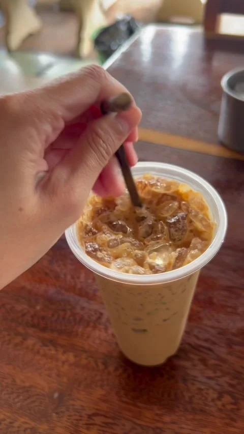 Hand Thrusting Straw Into Iced Milk Tea Coffee Close Up Video stock 243333684