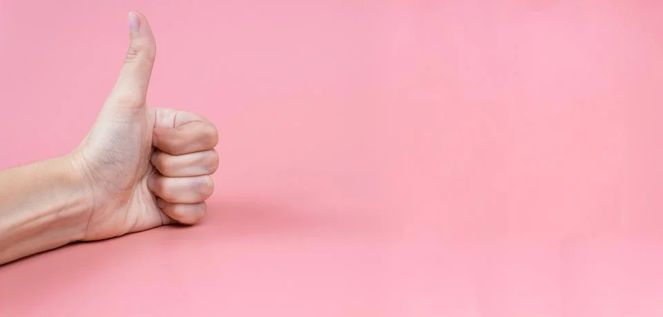 Hand with thumbs up on a pink background close up. Copy space. Banner Stock Photos