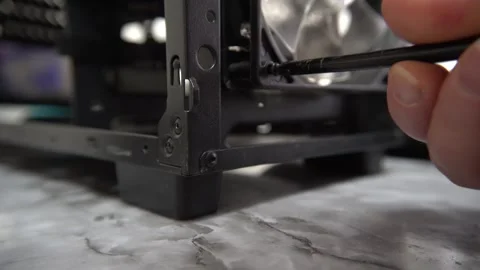 The hand tightens the bolt at the base of the computer case. Stock Footage 328529147
