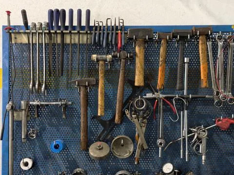 Hand tools and diagnostic equipment hanging on a blue pegboard wall 库存照片