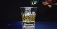 A Hand Tosses Ice Cubes Into A Glass On A Bar Then Pours Alcohol Stock Footage